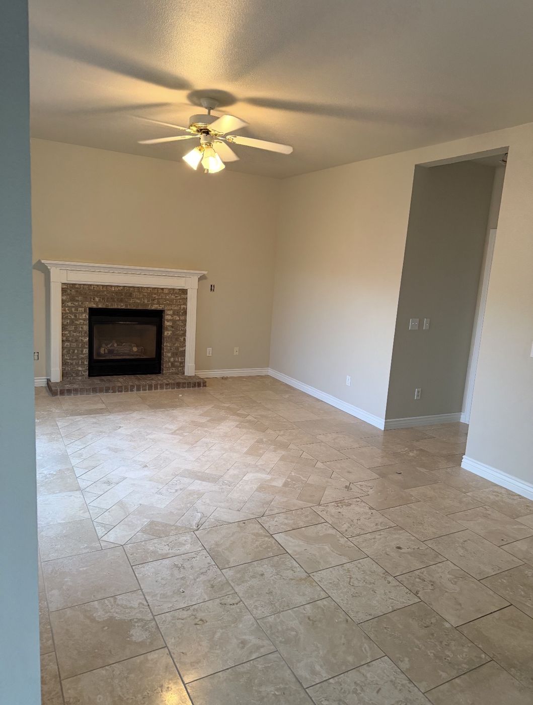 Freshly painted living room with neutral walls, white baseboards and fireplace mantel