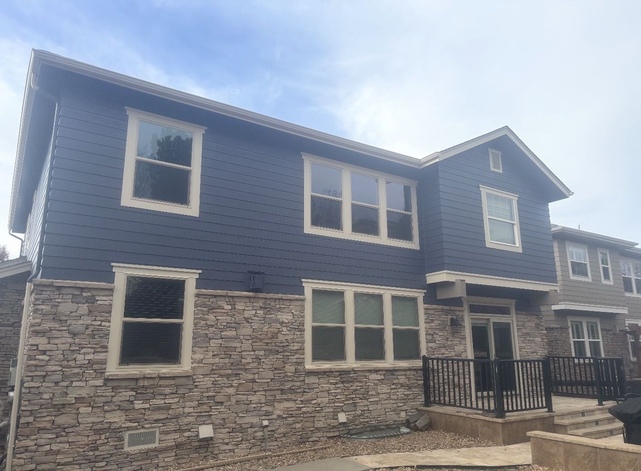 Back of the navy home with cream window trim and stone base